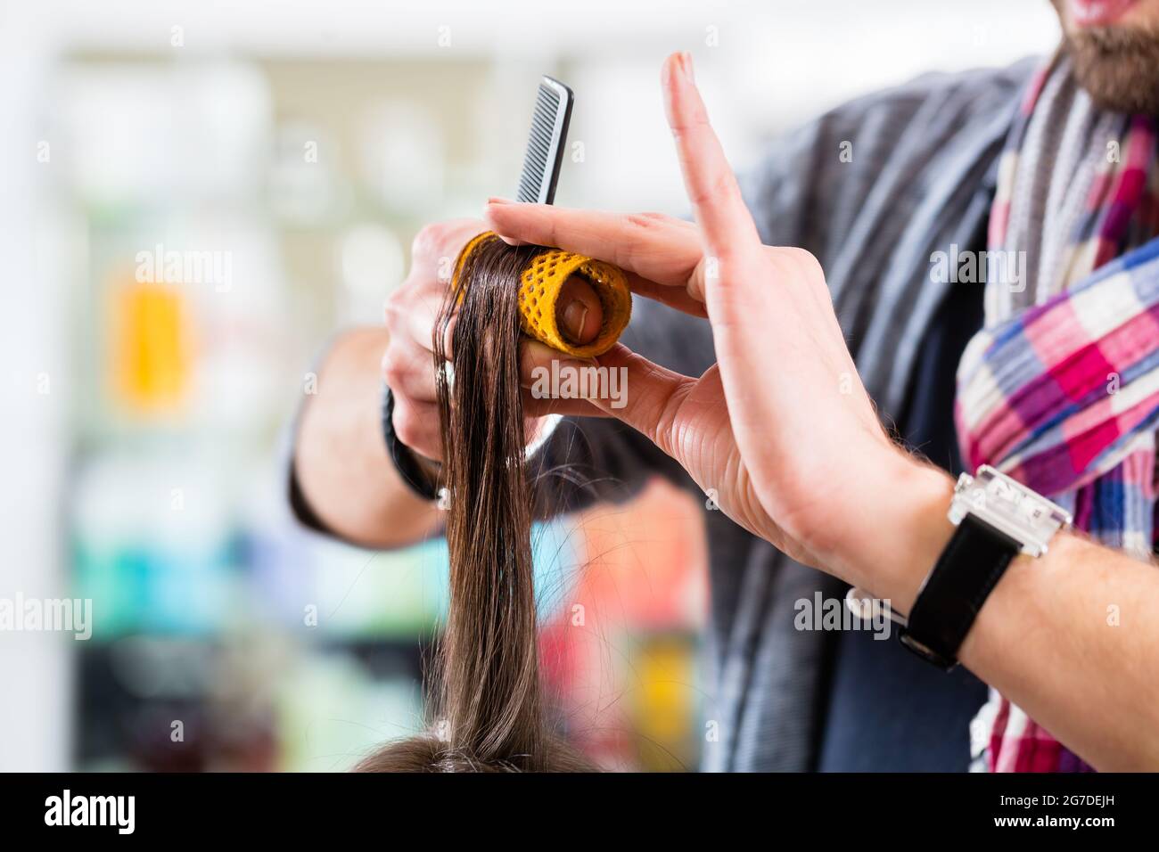 Maschio abito coiffeur donna capelli con rullo in negozio Foto Stock