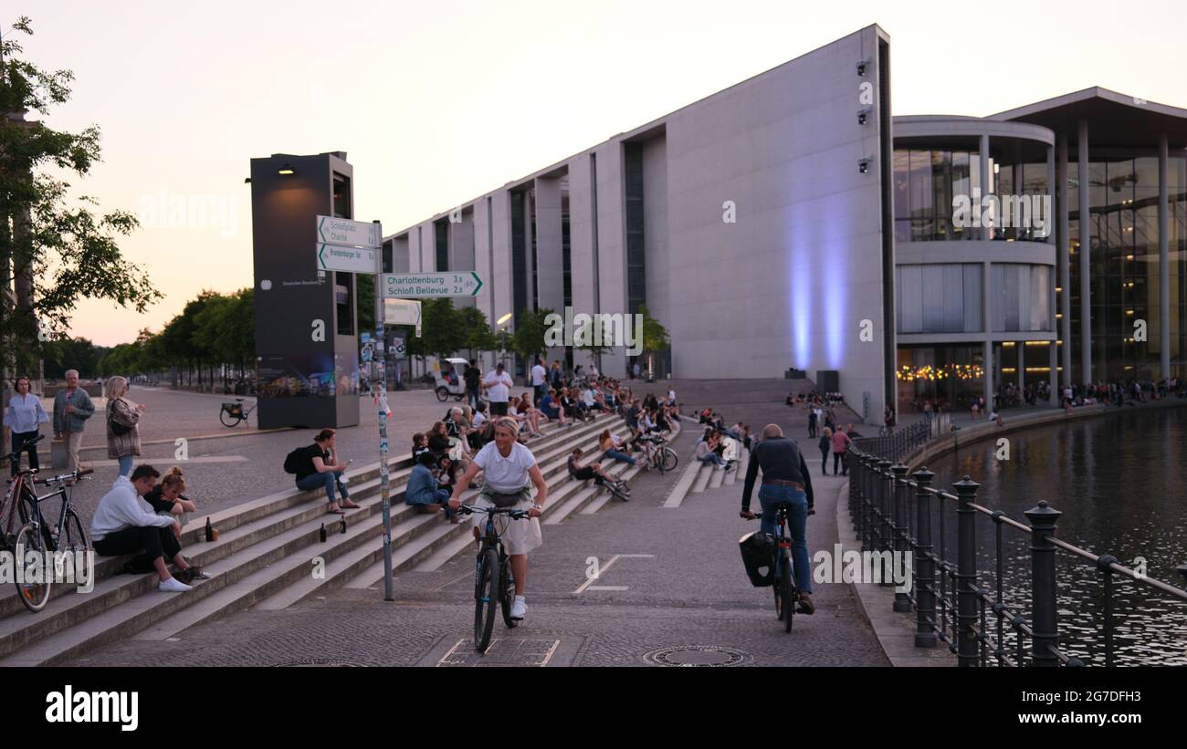 BERLINO, GERMANIA - 26 giu 2021: Un gruppo di persone che riposano sui gradini e in bicicletta per le strade di Berlino, Germania Foto Stock