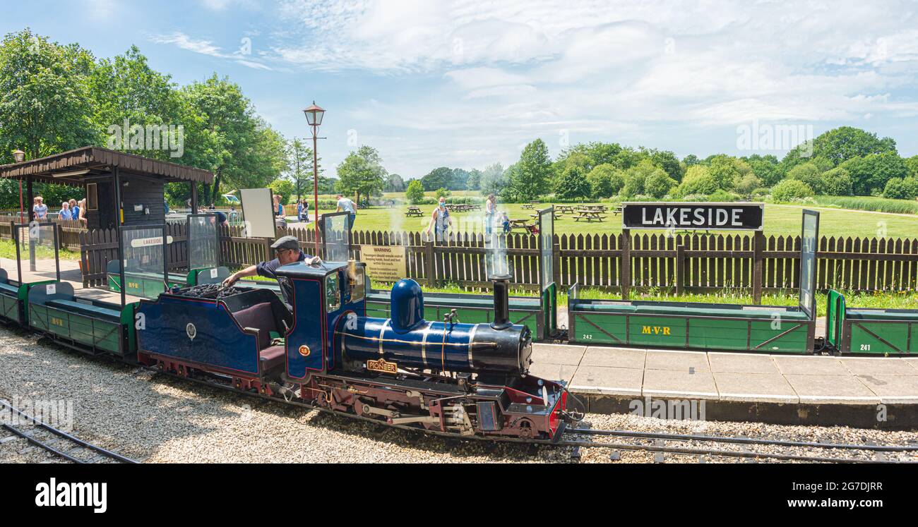 L'autista di un motore a vapore aggiunge carbone al treno a vapore in miniatura presso la stazione di Lakeside nel Moors Valley Country Park, dove le persone si accodano per fare un giro. Foto Stock