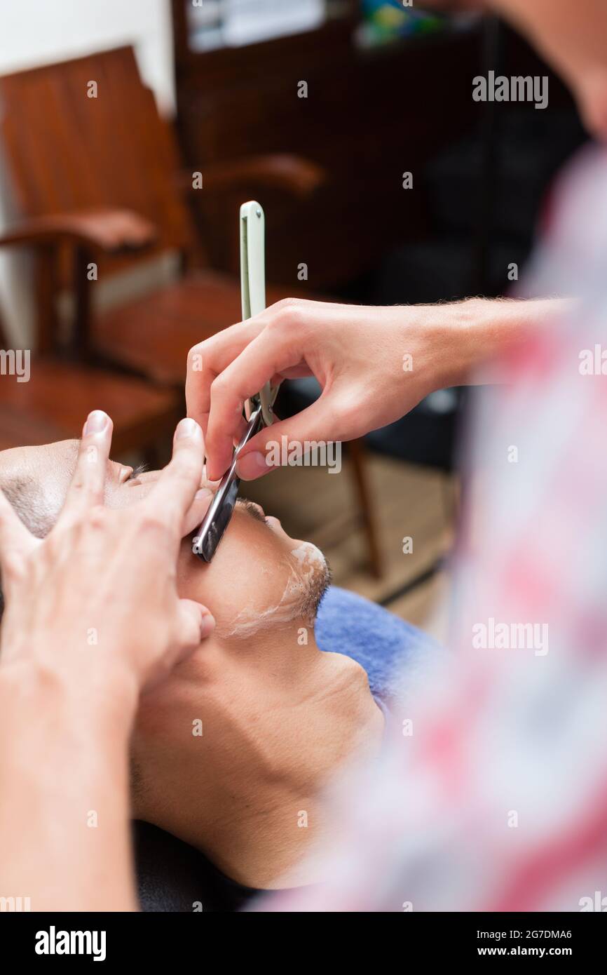 Primo piano della rasatura professionale del barbiere con rasoio in salone di bellezza Foto Stock