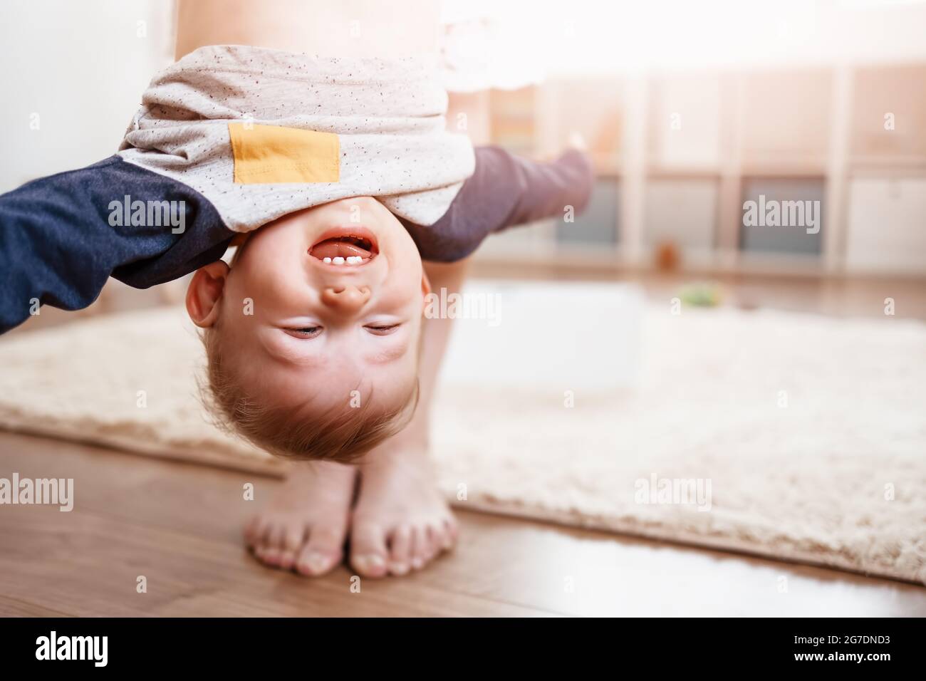 Madre che tiene capovolta il suo bambino ridente. Foto Stock