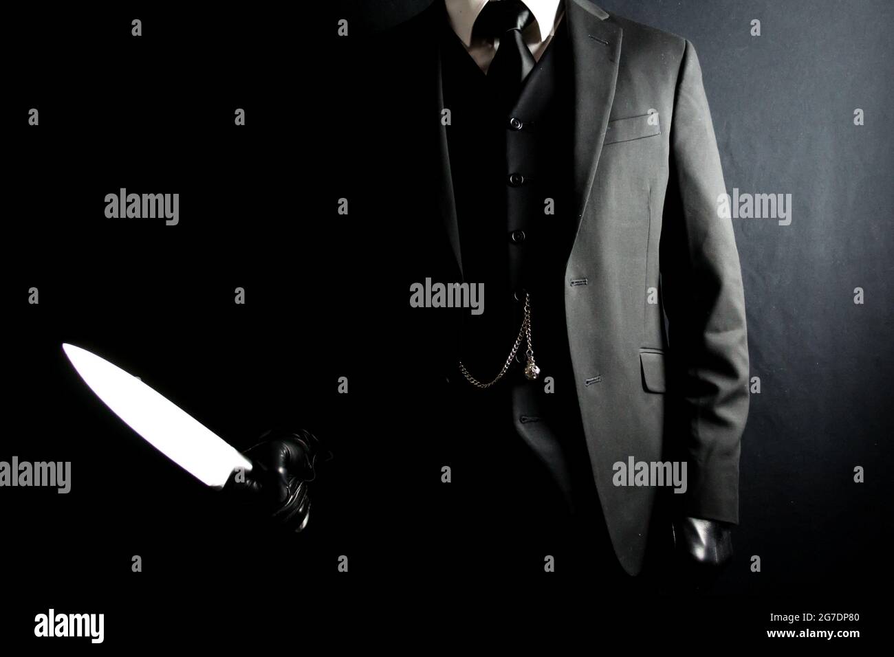 Ritratto di uomo in tuta scura e guanti in pelle che tiene il coltello affilato su sfondo nero. Ben vestito Gentleman Killer. Mafia Hit Man in abito elegante. Foto Stock