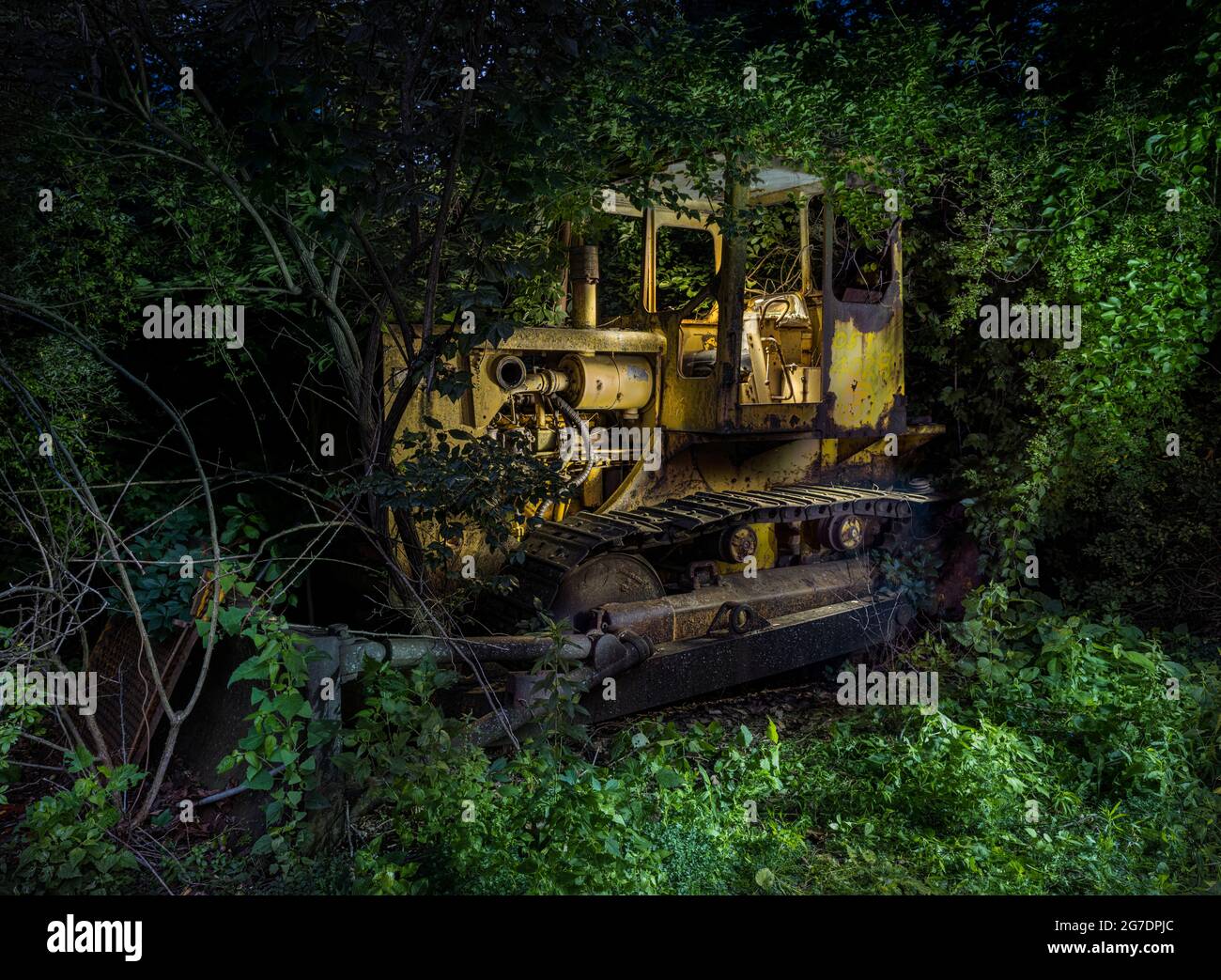 Bulldozer abbandonato nelle erbacce di notte Foto Stock