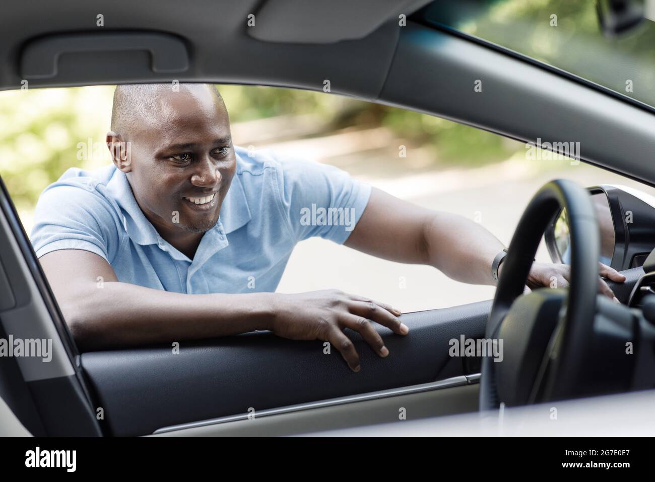 Felice uomo afroamericano che guarda all'interno di una nuova auto Foto Stock