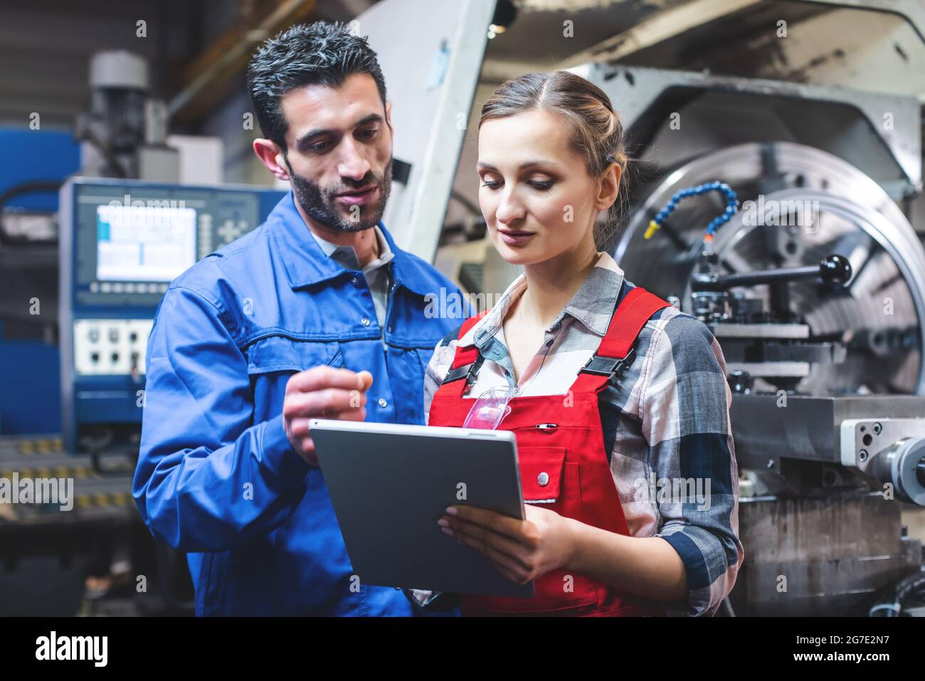 Donna e uomo lavoratore di fabbricazione in discussione la scrittura su tablet PC Foto Stock