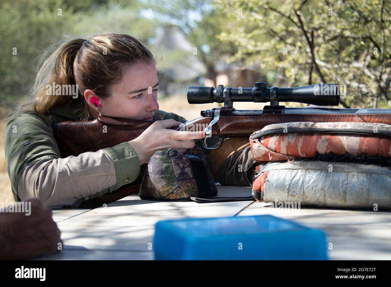 Donna che punta un fucile su una panca di tiro. Foto Stock