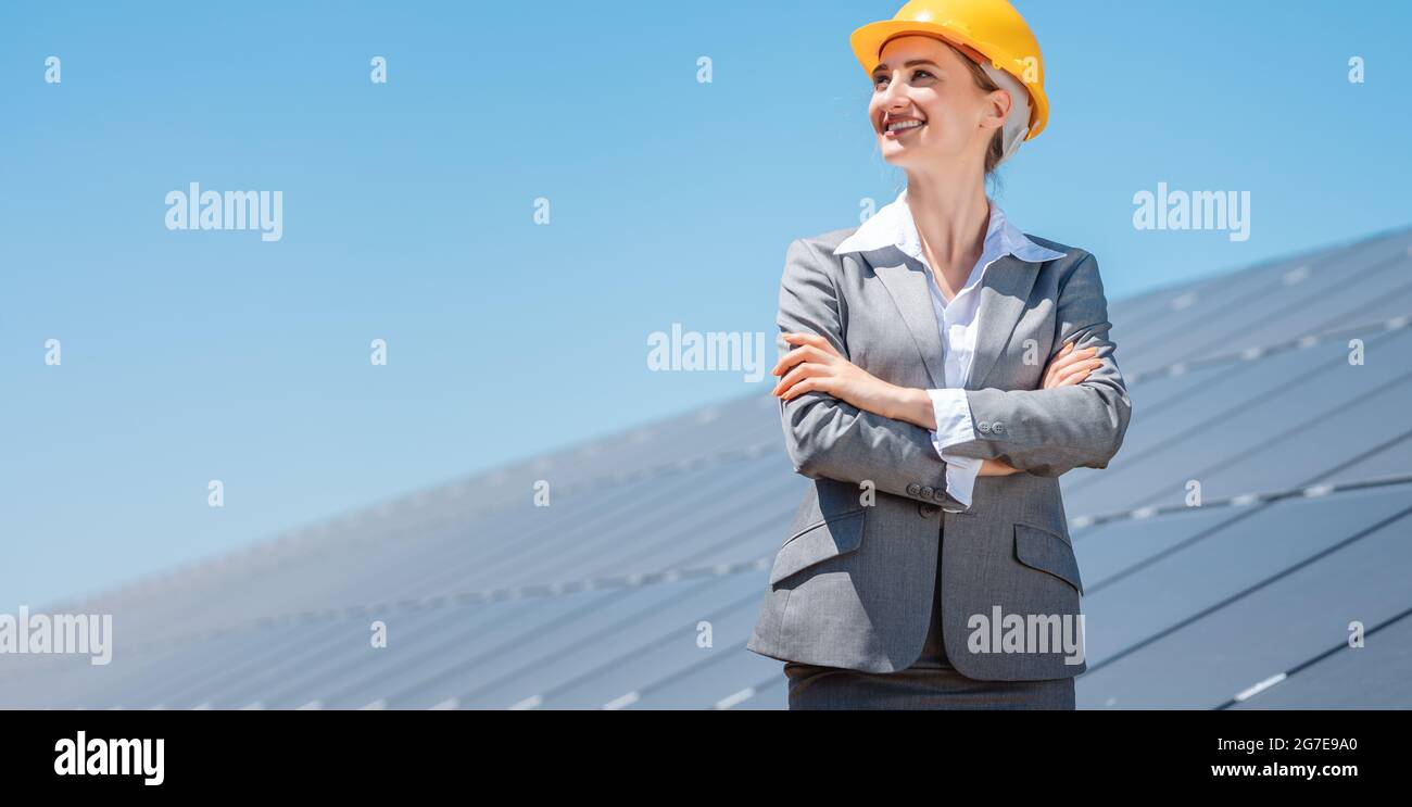 Investitore donna in energia pulita in piedi orgogliosamente di fronte a pannelli solari Foto Stock