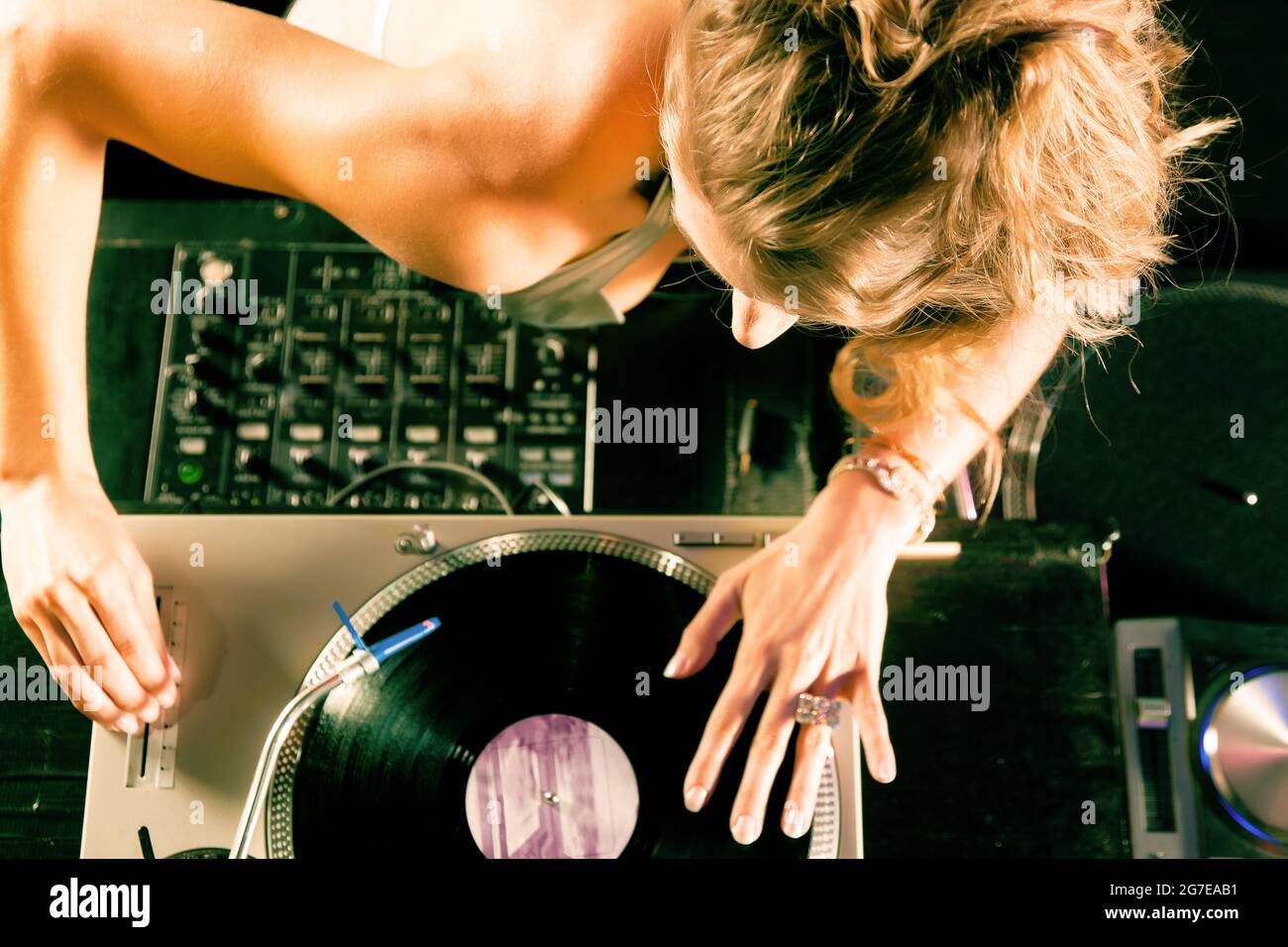 DJ femminile al giradischi in un club, con mixer e vecchio giocatore di record della scuola Foto Stock