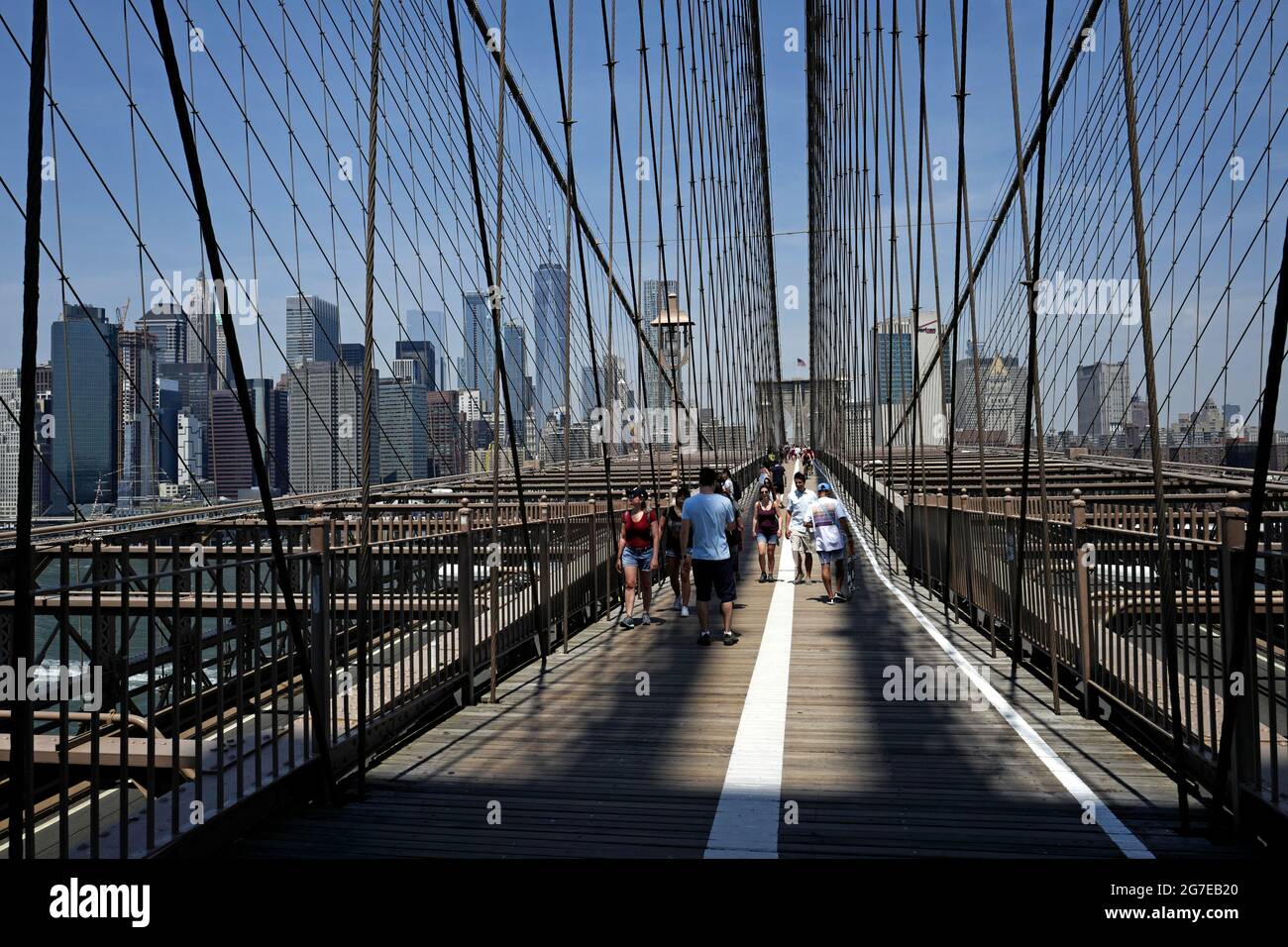 Passeggia lungo la corsia e la pista ciclabile sul ponte di Brooklyn, con il cielo blu sullo skyline di Manhattan, a New York City. Foto Stock