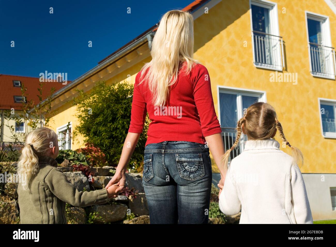 Madre con due bambini in piedi davanti a loro nuova casa Foto Stock
