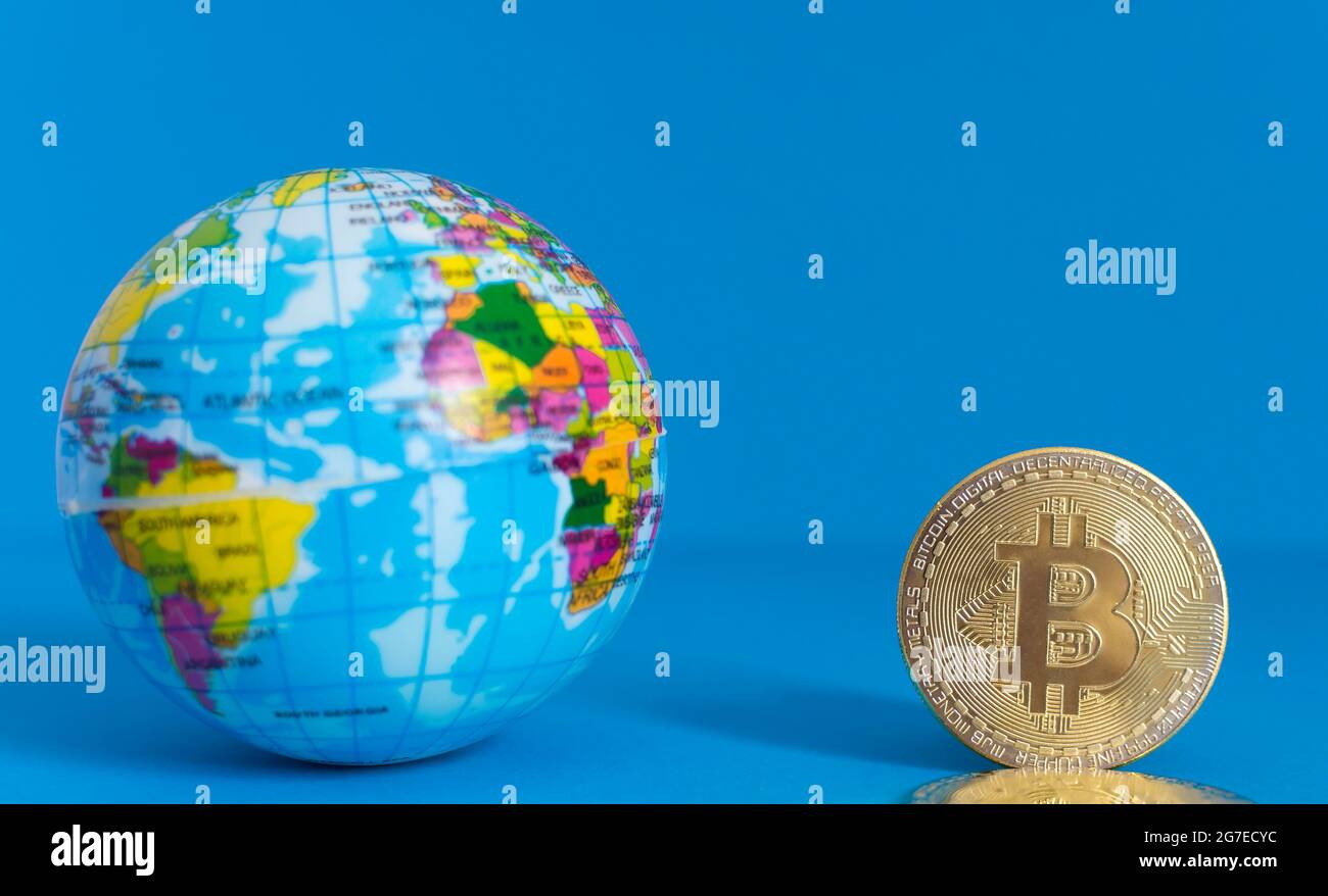 Bitcoin BTC moneta d'oro criptovaluta e globo terrestre, nuovo concetto di moneta virtuale a livello mondiale. Tecnologia mineraria o blockchain Foto Stock