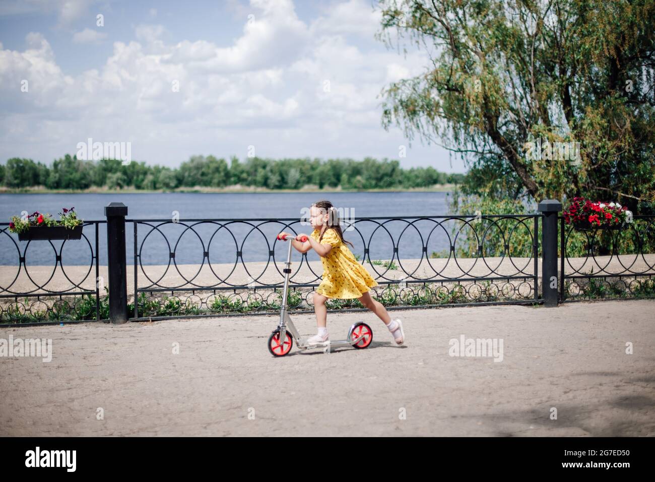 sport urbani e attività per la famiglia, una ragazza guida rapidamente uno scooter, una ragazza su uno scooter sul terrapieno in un ambiente urbano Foto Stock