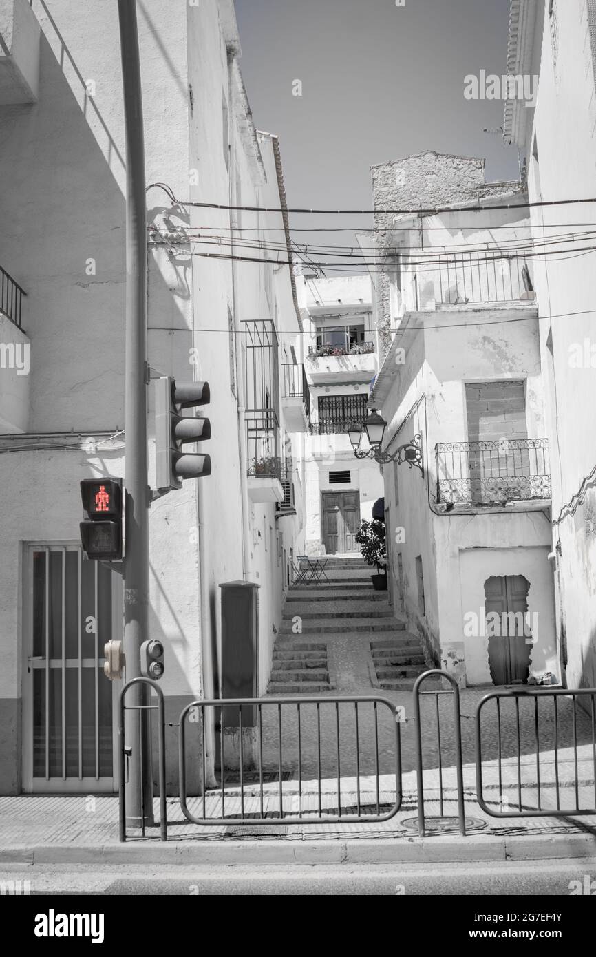 Scena stradale con scalini tra gli edifici con linee elettriche attraversate e spia rossa di attraversamento ad Altea, Alicante Spagna Foto Stock