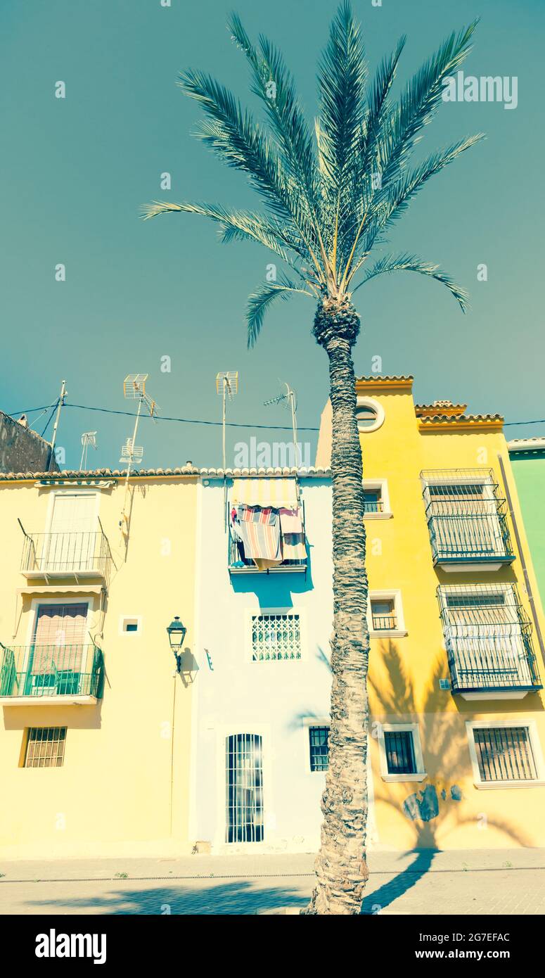 Immagine retrò sbiadita fila di colori pastello stile terrazza tradizionale case mediterranee con palme la Vila Joiosa, Alicante Spagna Foto Stock