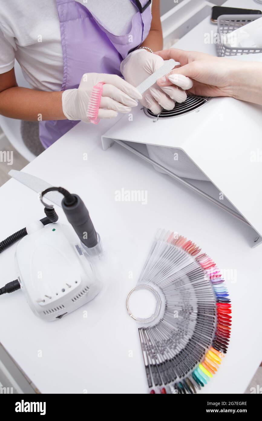 Vista dall'alto verticale ripresa ritagliata del tavolo dei manicuristi con tavolozza di smalto per unghie e punta per unghie Foto Stock