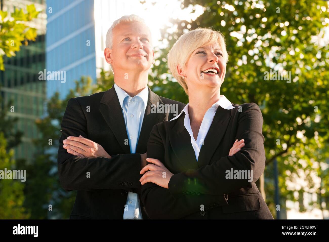 La gente di affari - maturo o senior - in piedi in un parco all'aperto di fronte ad un edificio per uffici Foto Stock