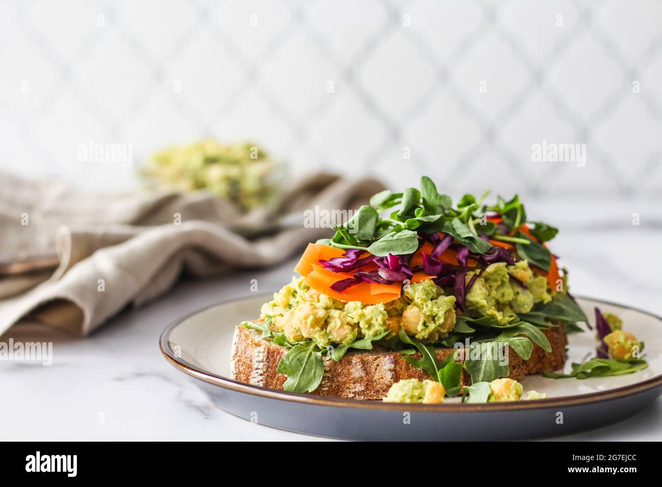 Panino vegetariano fresco con carote, cavolo, germogli di piselli e insalata di ceci su un piatto Foto Stock