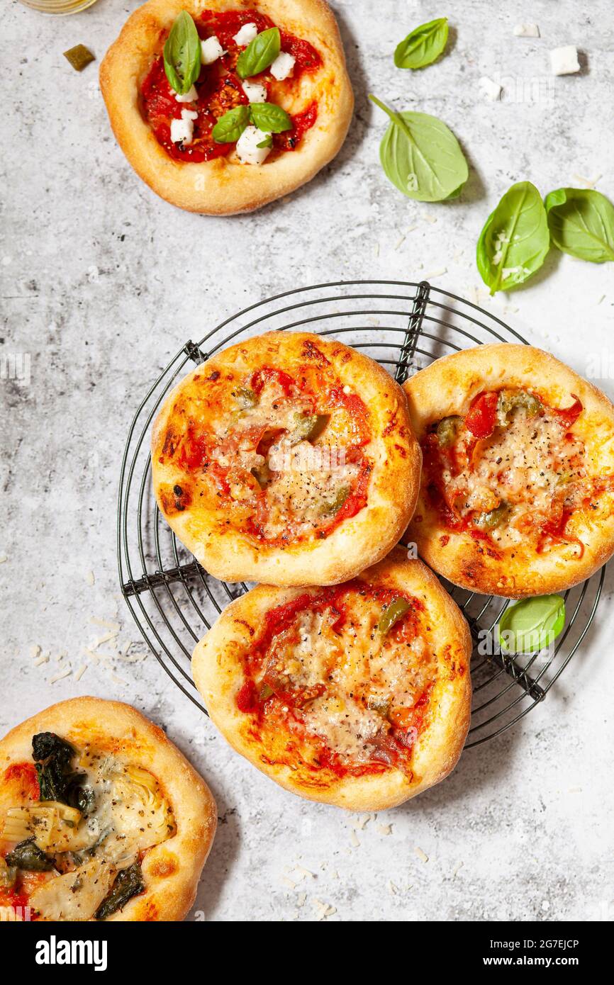 Mini pizze - pizzette - condite con formaggio e pomodoro più prosciutto italiano e peperoncino Foto Stock