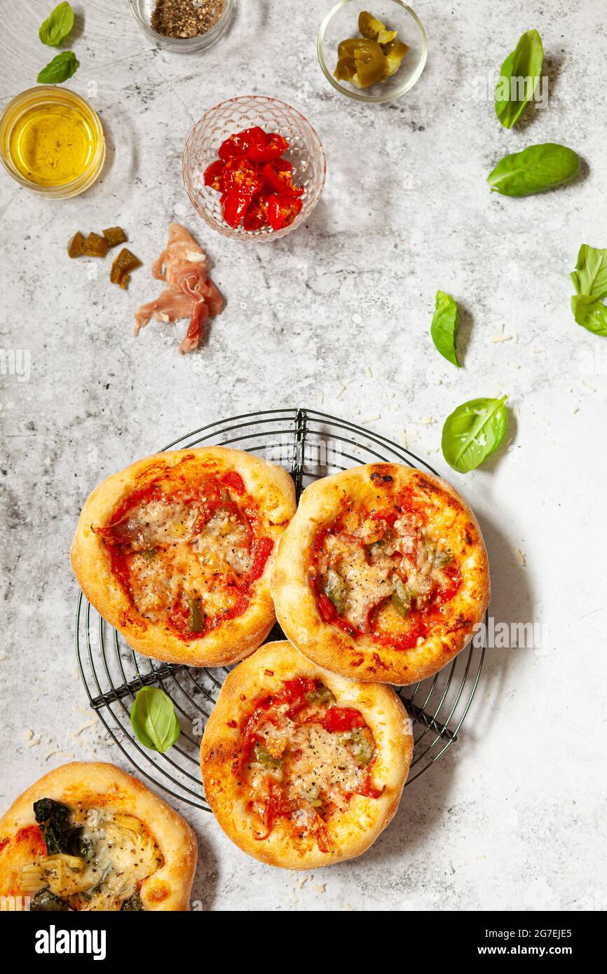 Mini pizze - pizzette - condite con formaggio e pomodoro più prosciutto italiano e peperoncino Foto Stock