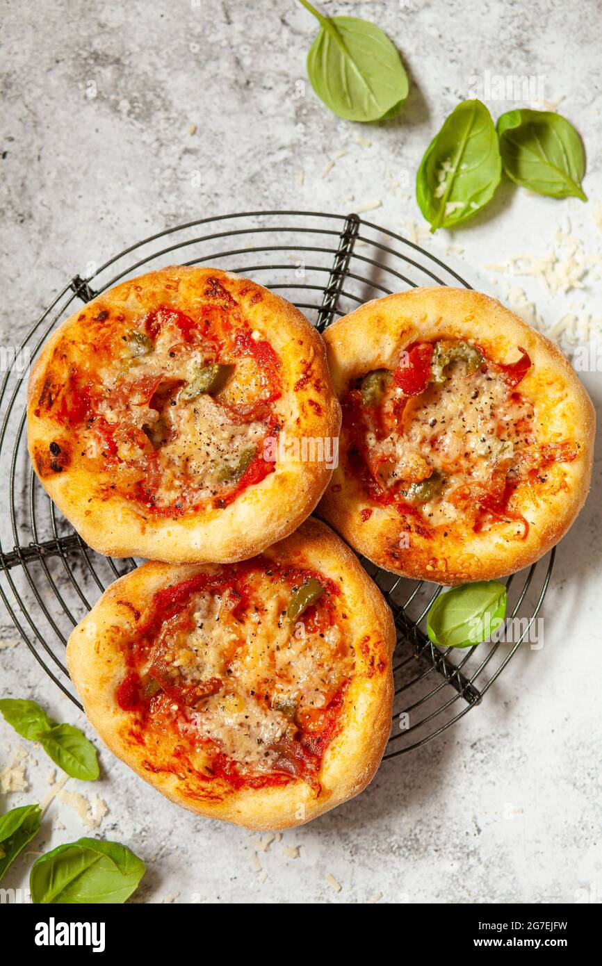 Mini pizze - pizzette - condite con formaggio e pomodoro più prosciutto italiano e peperoncino Foto Stock