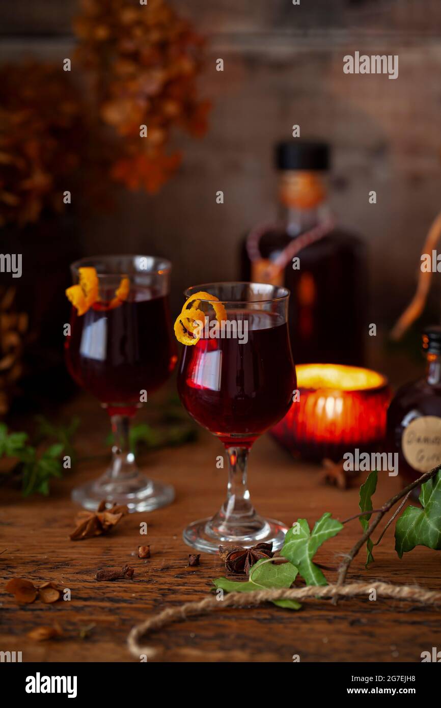 Bicchieri di liquore damson gin serviti in bicchieri di sherry con un tocco di scorza d'arancia. Foto Stock