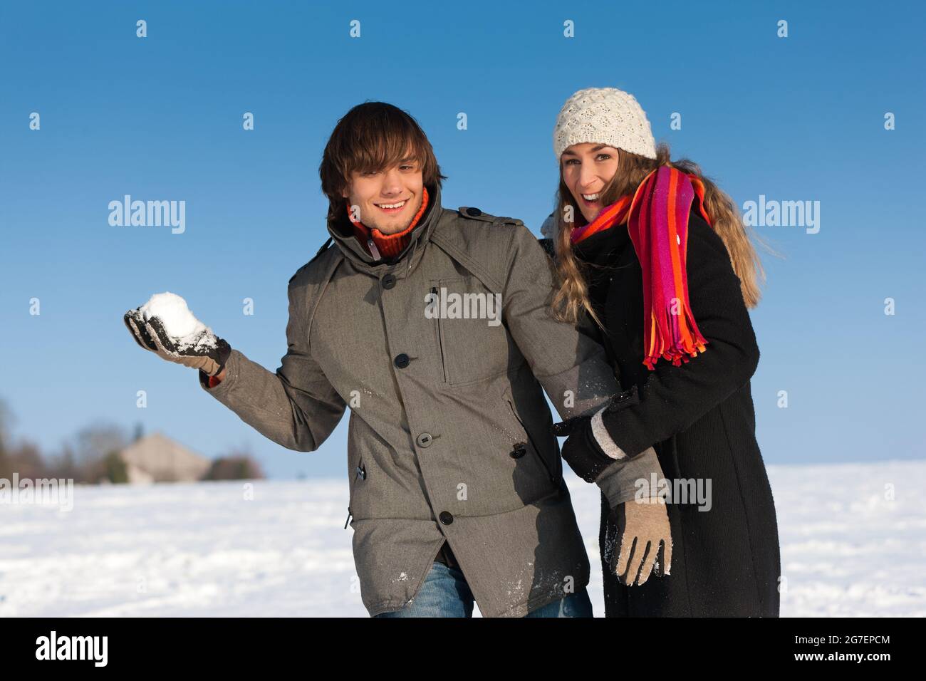 Coppia - uomo e donna - facendo una passeggiata invernale e gettando la neve Foto Stock