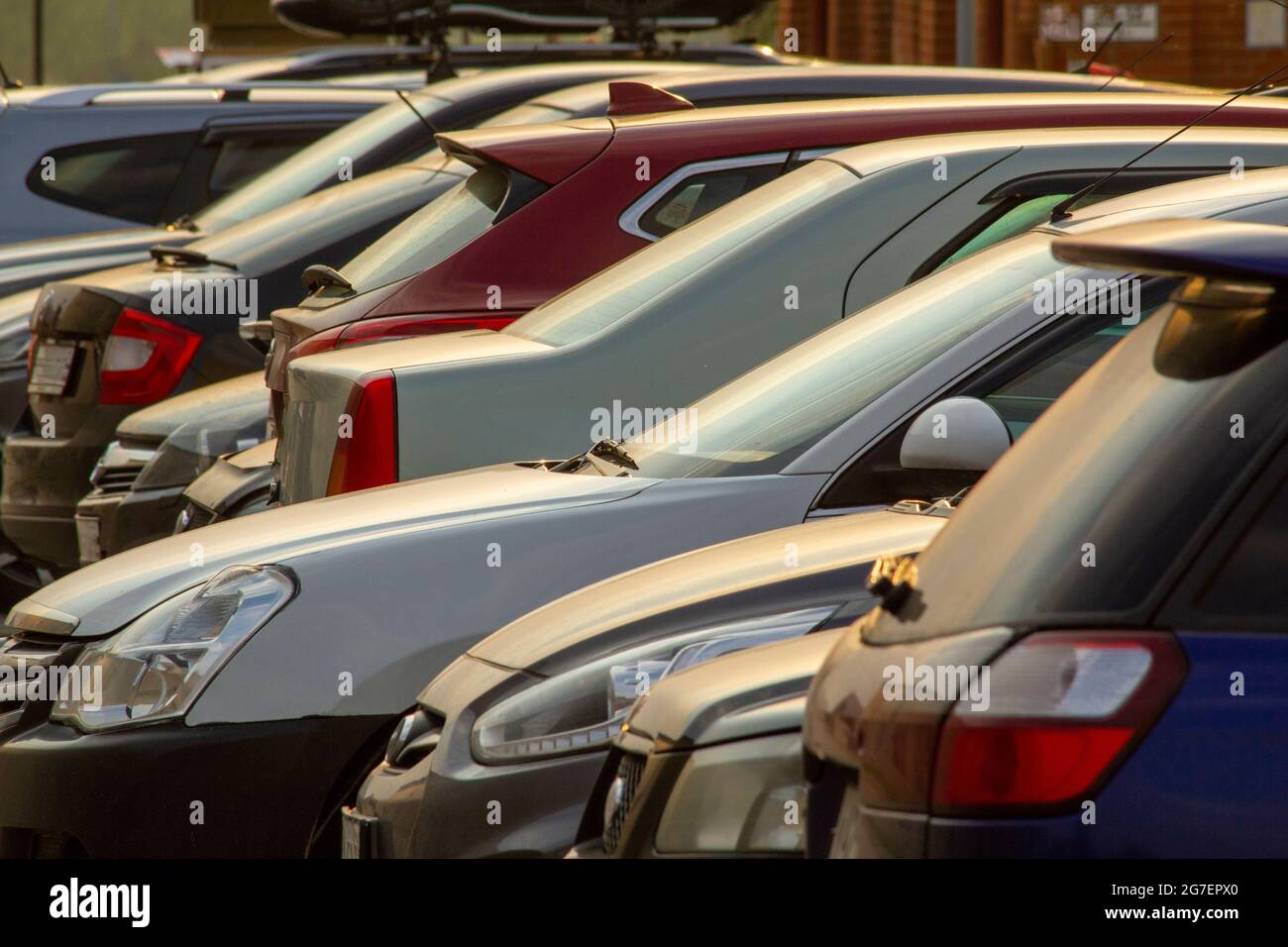 I contorni delle auto che si levano in piedi in una fila nei raggi del tramonto. Foto Stock