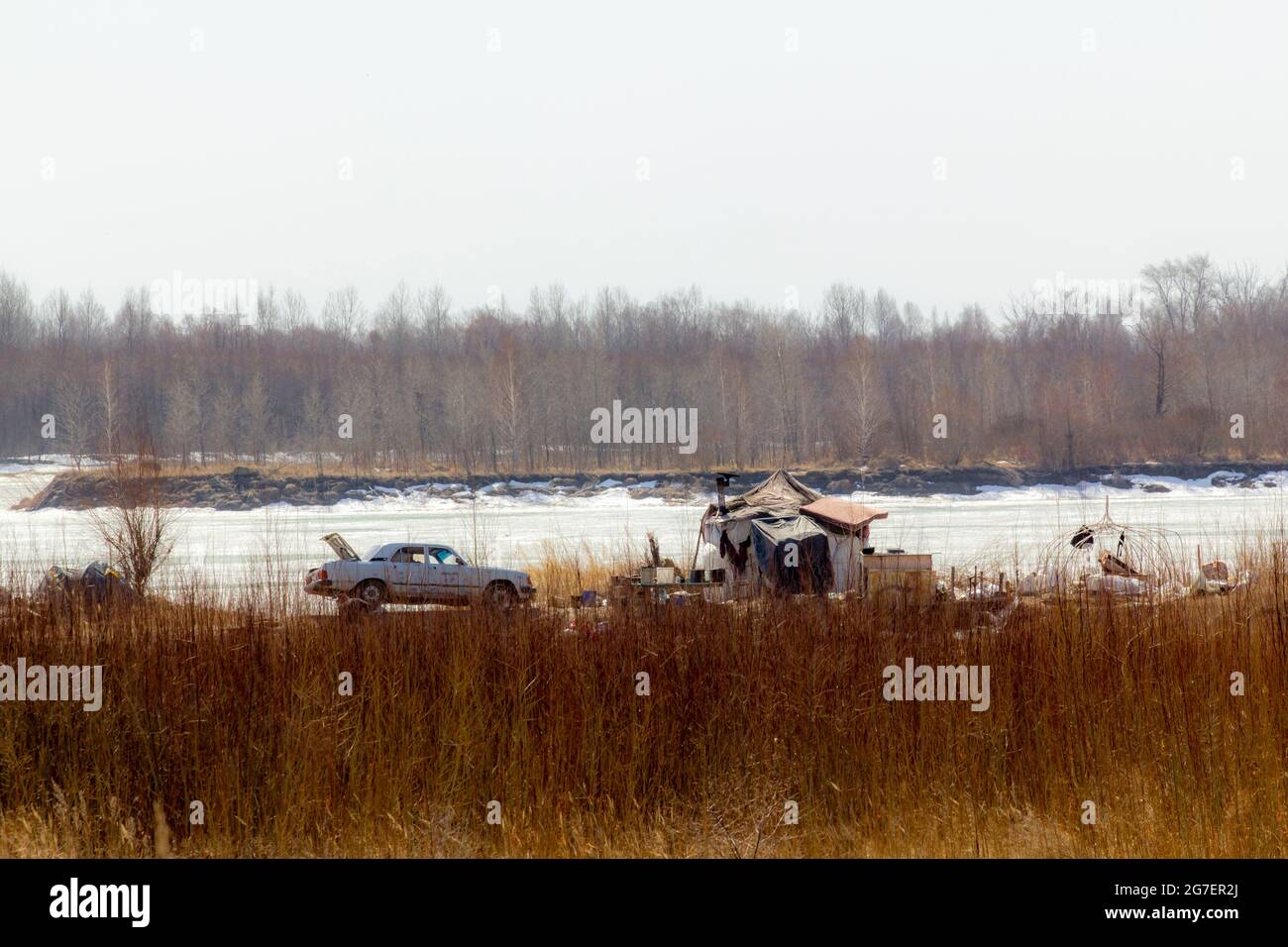 Una casa invernale dei rifugiati industriali e la sua vecchia auto arrugginita. Foto Stock