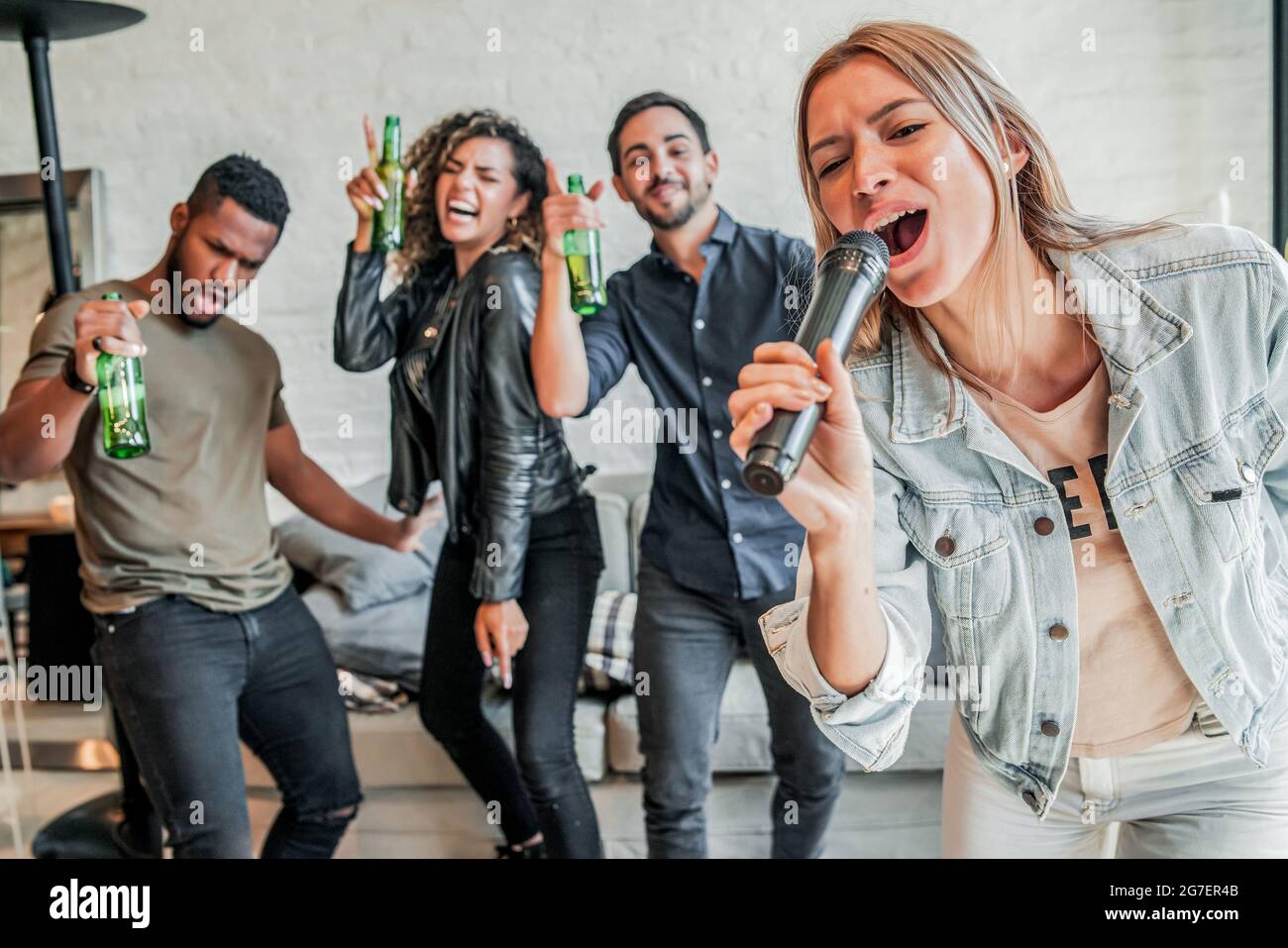 Gruppo di amici che giocano al karaoke a casa. Foto Stock