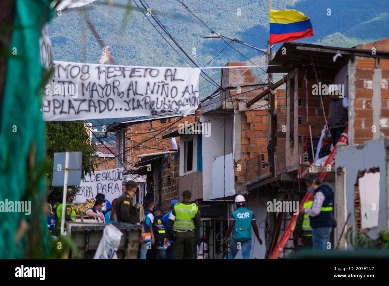 La gente appende segnali per evitare lo sfratto in un'area pericolosa di costruzione, i servizi per bambini della Colombia (ICBF) e la polizia riota (ESMAD) sfracano le famiglie che vivono in un quartiere a basso reddito indangered per crollare a causa del terreno a Itagui, Antioquia - Colombia. 12 luglio 2021 Foto Stock