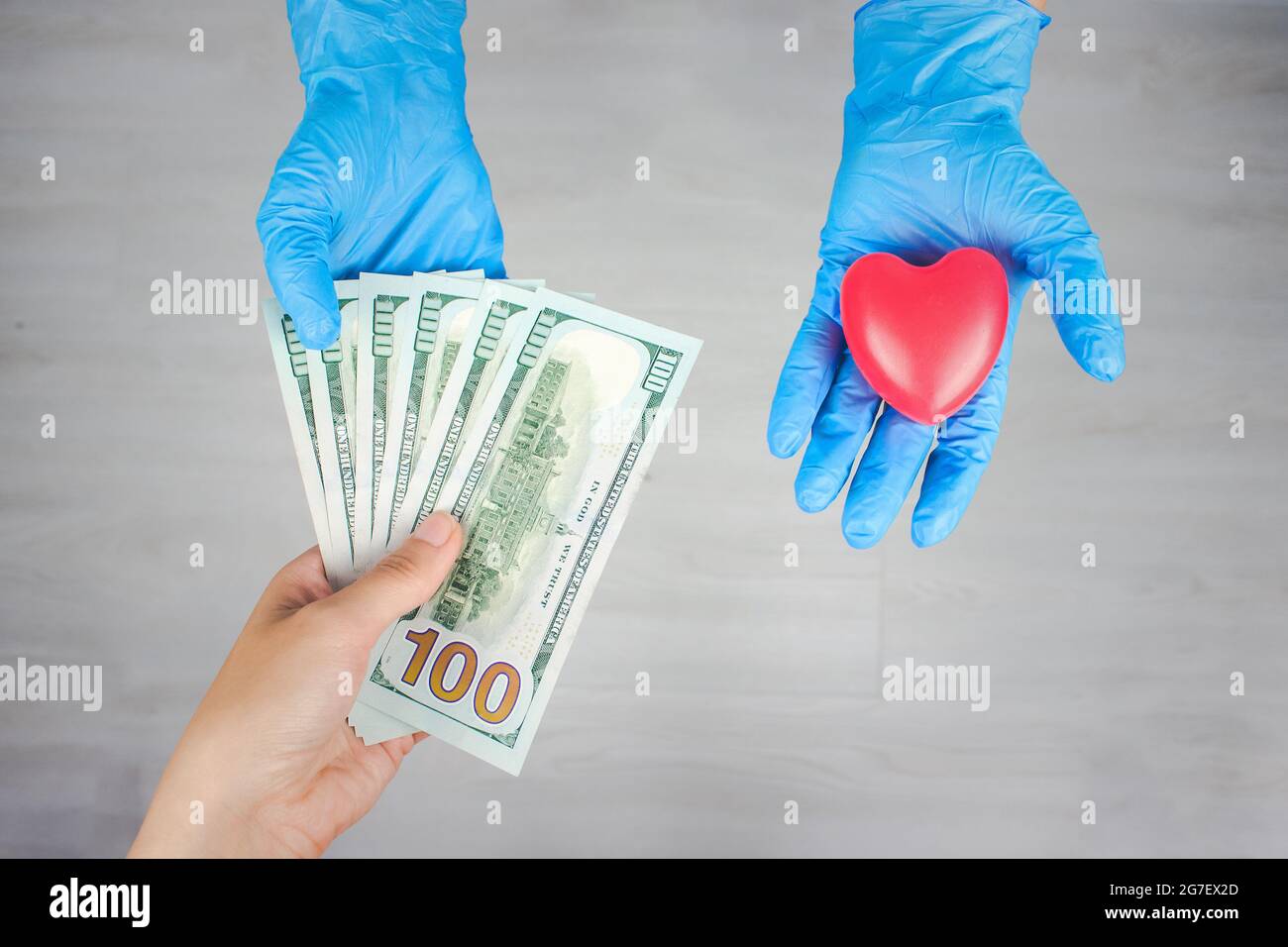 Donna medico mani in guanti blu ha preso soldi invece di cuore. Corruzione nell'assistenza sanitaria. Medicina a pagamento. Costi per l'assicurazione medica. Foto Stock