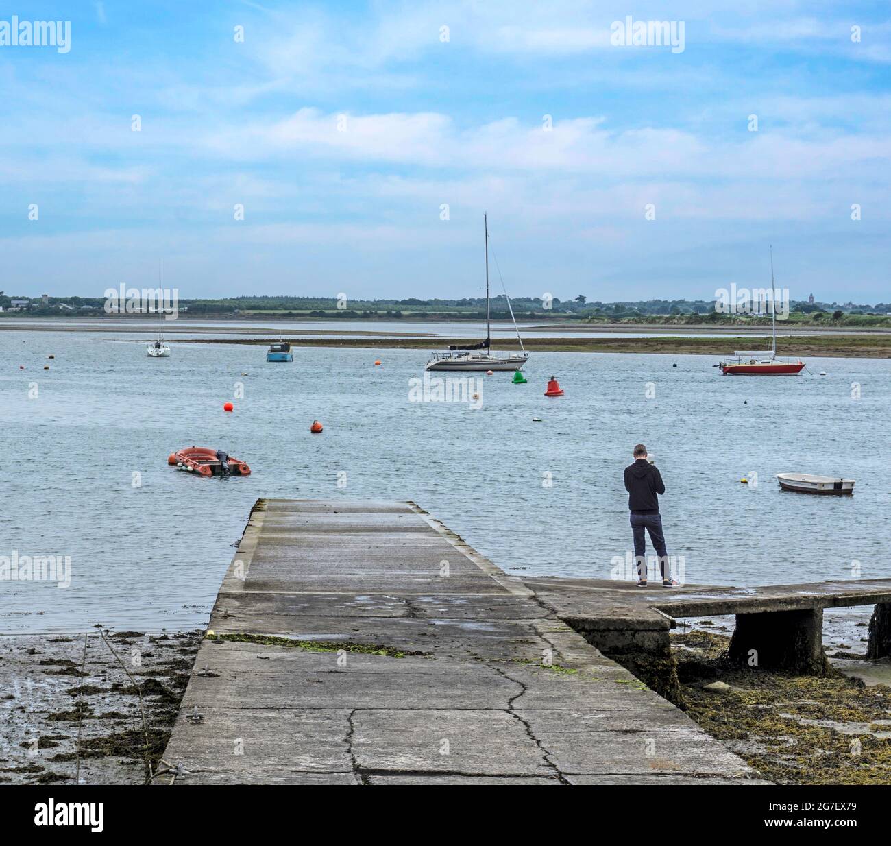 Un uomo che guarda fuori al mare nell'estuario di Malahide a Dublino, Irlanda. Foto Stock