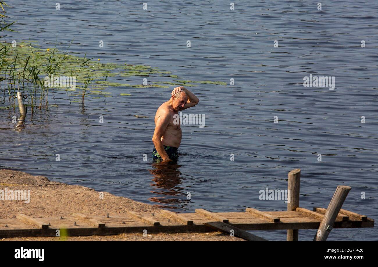 Riga, Lettonia. 13 luglio 2021. Un uomo si raffredda in un fiume a riga, Lettonia, il 13 luglio 2021. Il Centro Latviano ambiente, Geologia e Meteorologia ha emesso un avvertimento rosso nel paese, che è in vigore fino a venerdì. Credit: Edijs Palens/Xinhua/Alamy Live News Foto Stock