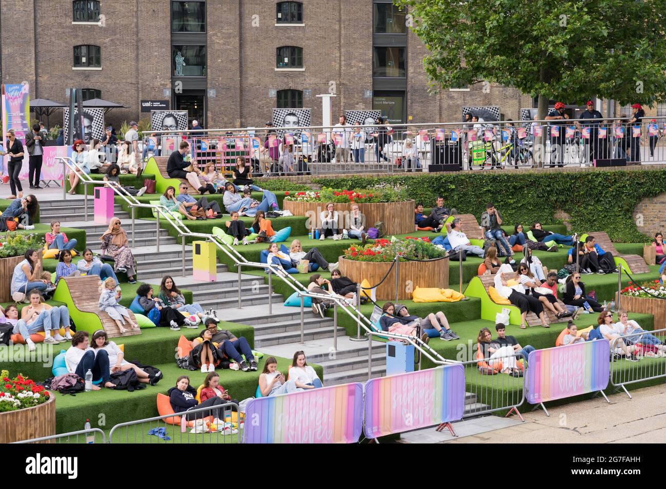Folli si rilassano sui gradini del lato canale di Granary Square durante una proiezione cinematografica all'aperto, King's Cross, Londra Foto Stock
