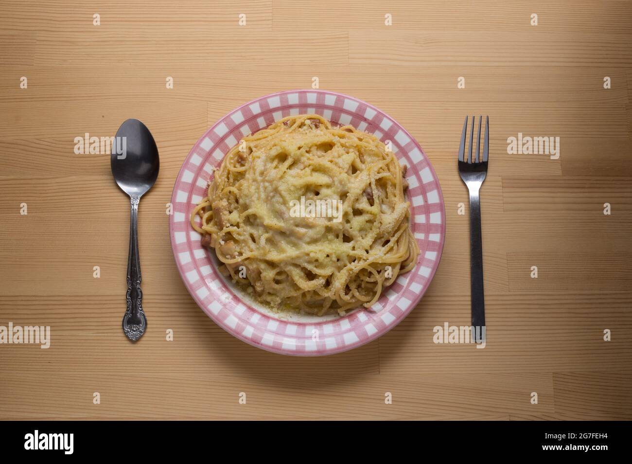 Vista dall'alto di un piatto con pasta di carbonara, con cucchiaio e forchetta. Foto Stock