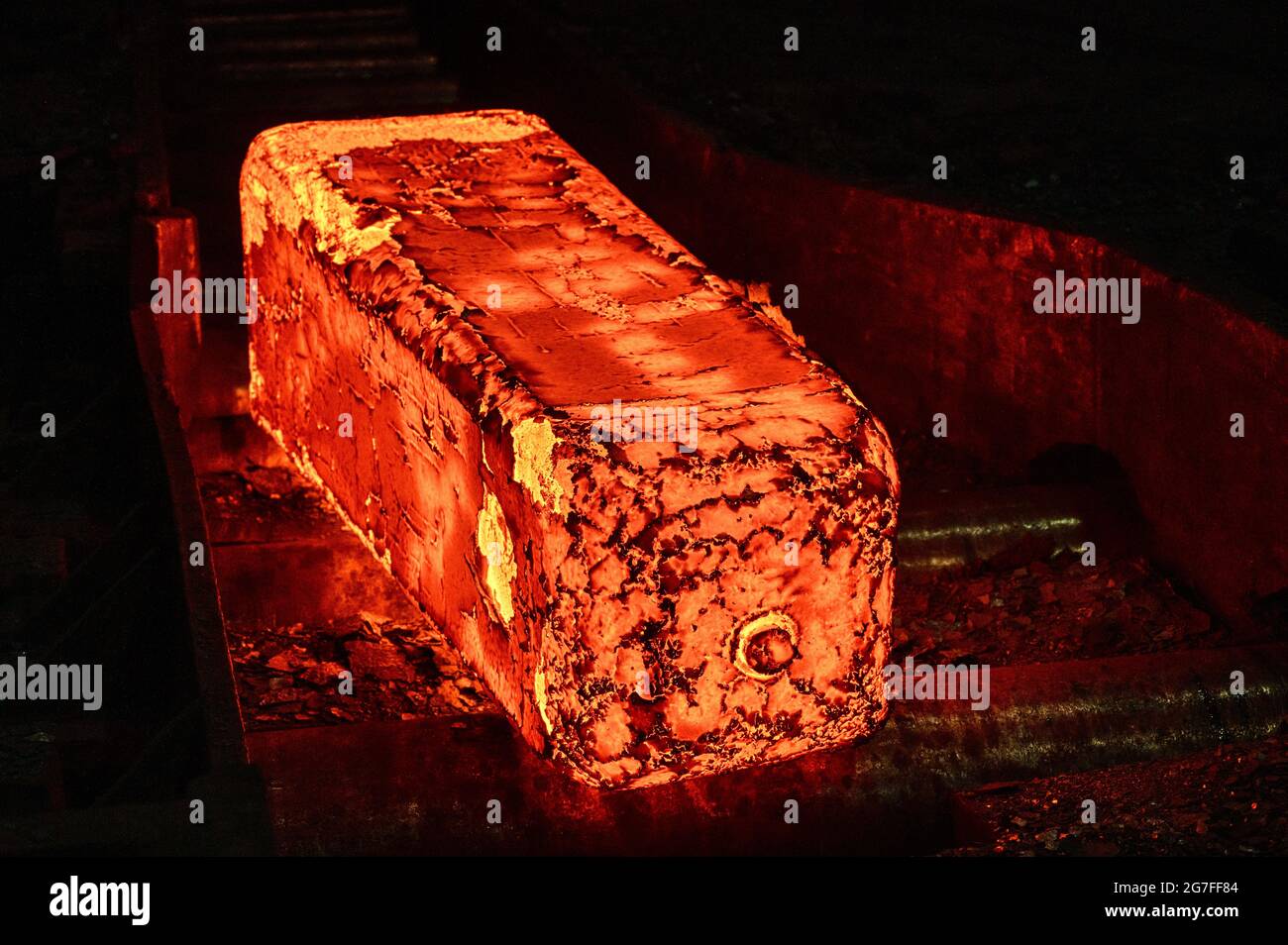 Billetta di metallo rosso-caldo sul tavolo a rulli di un laminatoio Foto Stock