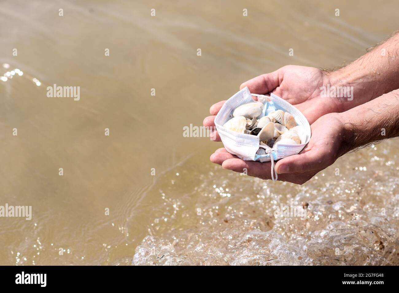 maschera medica nelle mani degli uomini con conchiglie Foto Stock