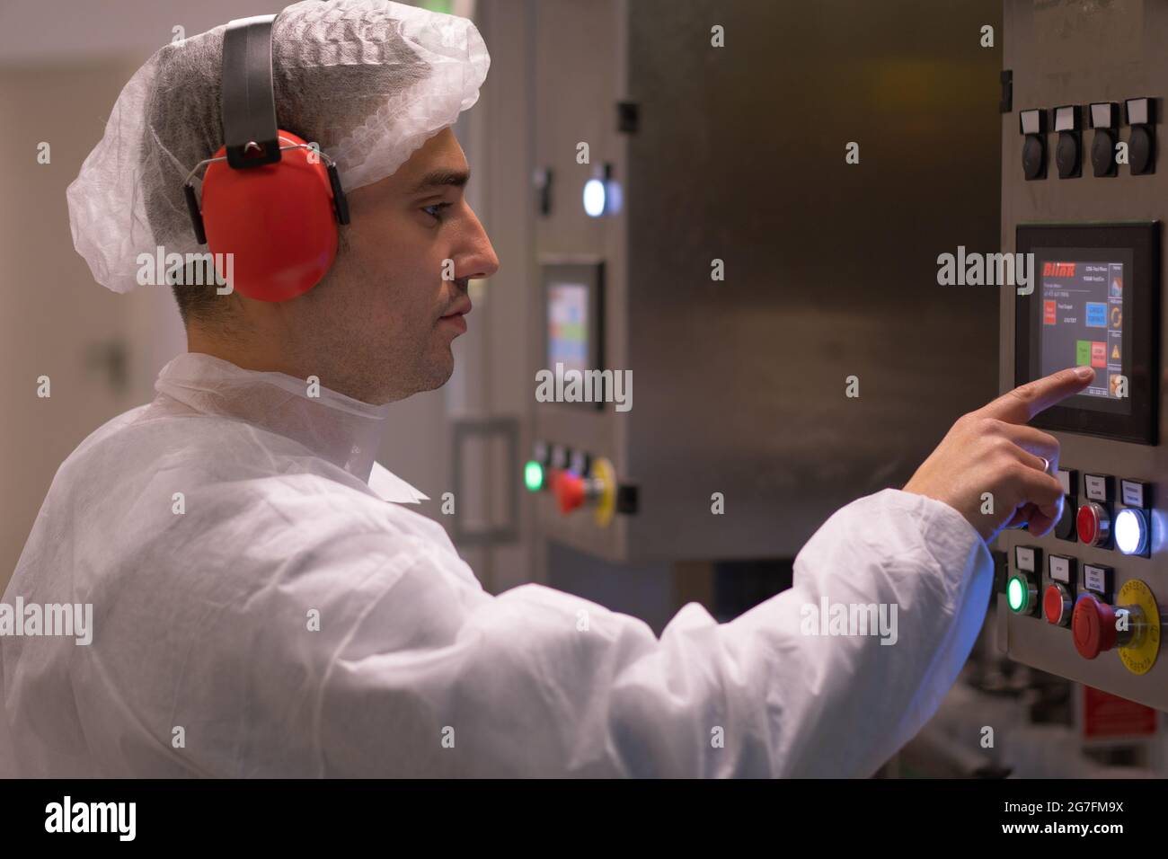 CAPUA, ITALIA - 04 luglio 2021: Giovane impiegato in abbigliamento sterile che opera su macchine industriali Foto Stock