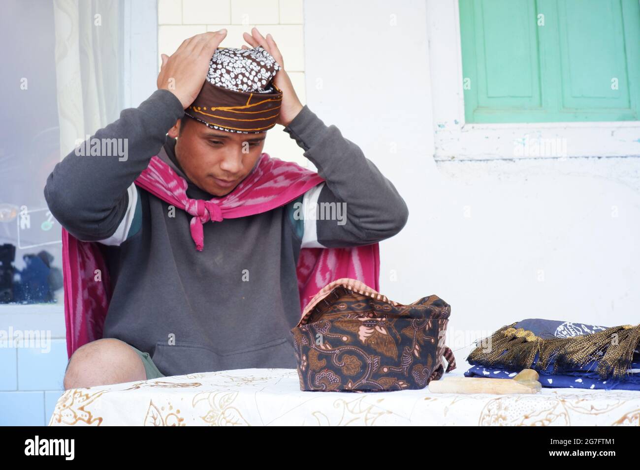 Pasuruan, Indonesia. Giugno 2021. Un uomo sta mettendo Udeng sulla testa. Udeng è un panno batik legato alla testa per la decorazione del Tenggerese e Javan Foto Stock