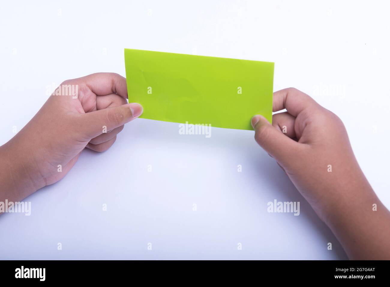Mano umana che piega una carta colorata isolata su sfondo bianco Foto Stock