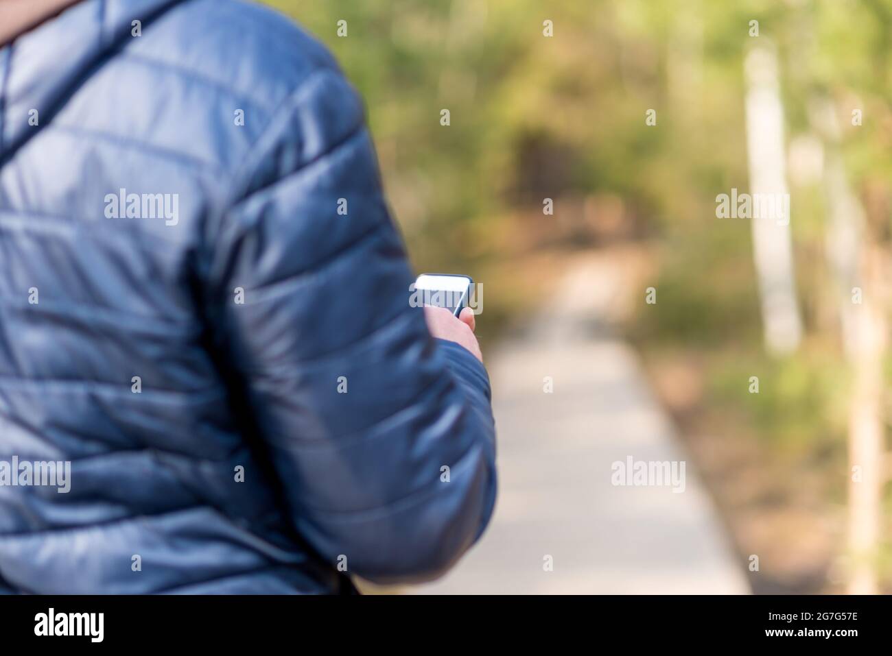 Un uomo di 40 anni con il suo smartphone cellulare alla ricerca del segnale di ricezione nella foresta primaverile. Foto Stock
