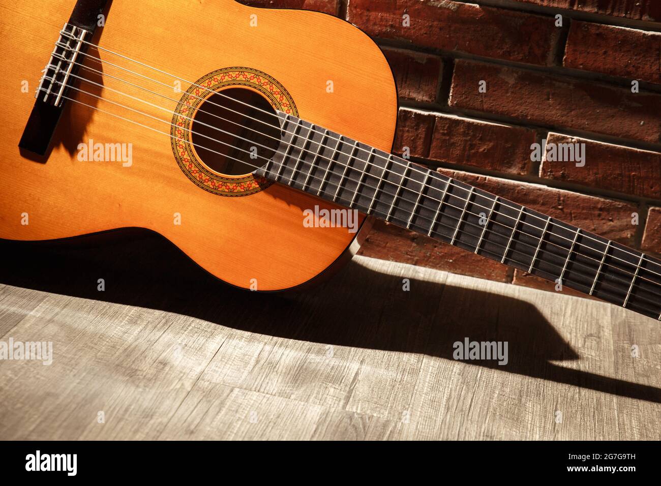 Dettaglio della chitarra classica su sfondo mattone Foto Stock