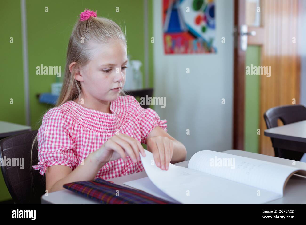 Studentessa caucasica seduta alla scrivania in classe che lavora durante la lezione Foto Stock