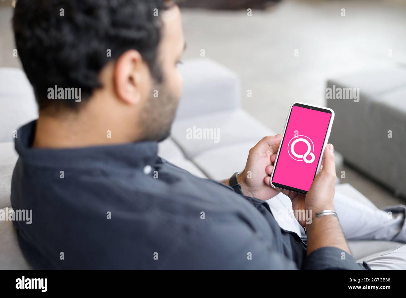 Kiev, Ucraina - 28 aprile 2021: Smartphone in mani maschili con Google Fuchsia OS sullo schermo, indio maschile freelance utilizzando il nuovo sistema operativo sul suo telefono Foto Stock