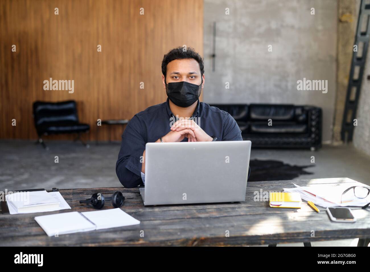 Headshot di uomo indù concentrato indossando maschera medica funziona con un computer portatile in ufficio. Il lavoratore maschile rimane al sicuro durante il periodo pandemico Foto Stock Headshot di uomo indù concentrato indossando maschera medica funziona con un computer portatile in ufficio. Il lavoratore maschile rimane al sicuro durante il periodo pandemico Foto Stock