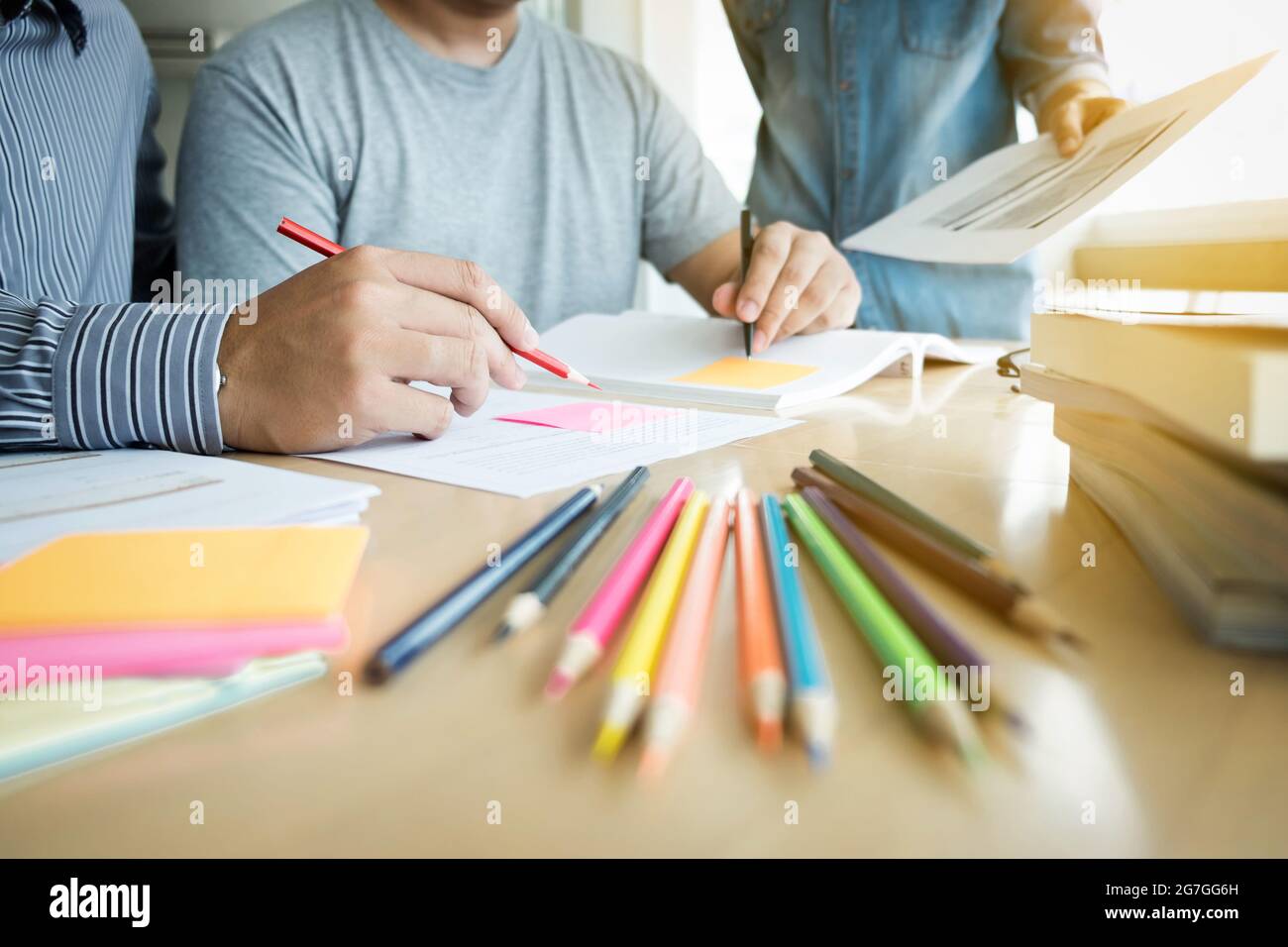 Educazione, insegnamento, apprendimento e concetto di persone. Gruppo di studenti delle scuole superiori o compagni di classe con aiuta gli amici a recuperare l'apprendimento del libro degli esercizi in classe Foto Stock