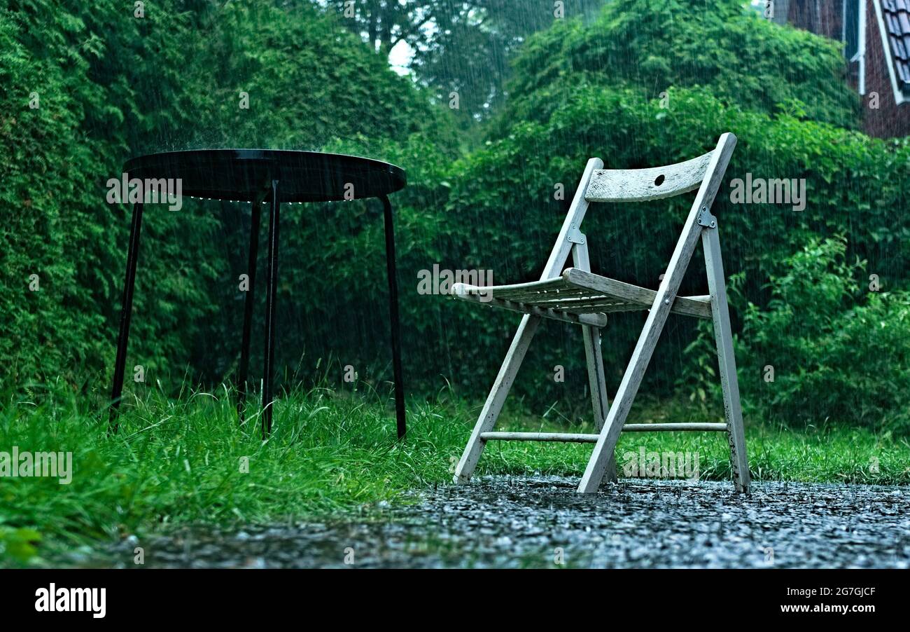 Una sedia vuota in un giardino durante un temporale Foto Stock