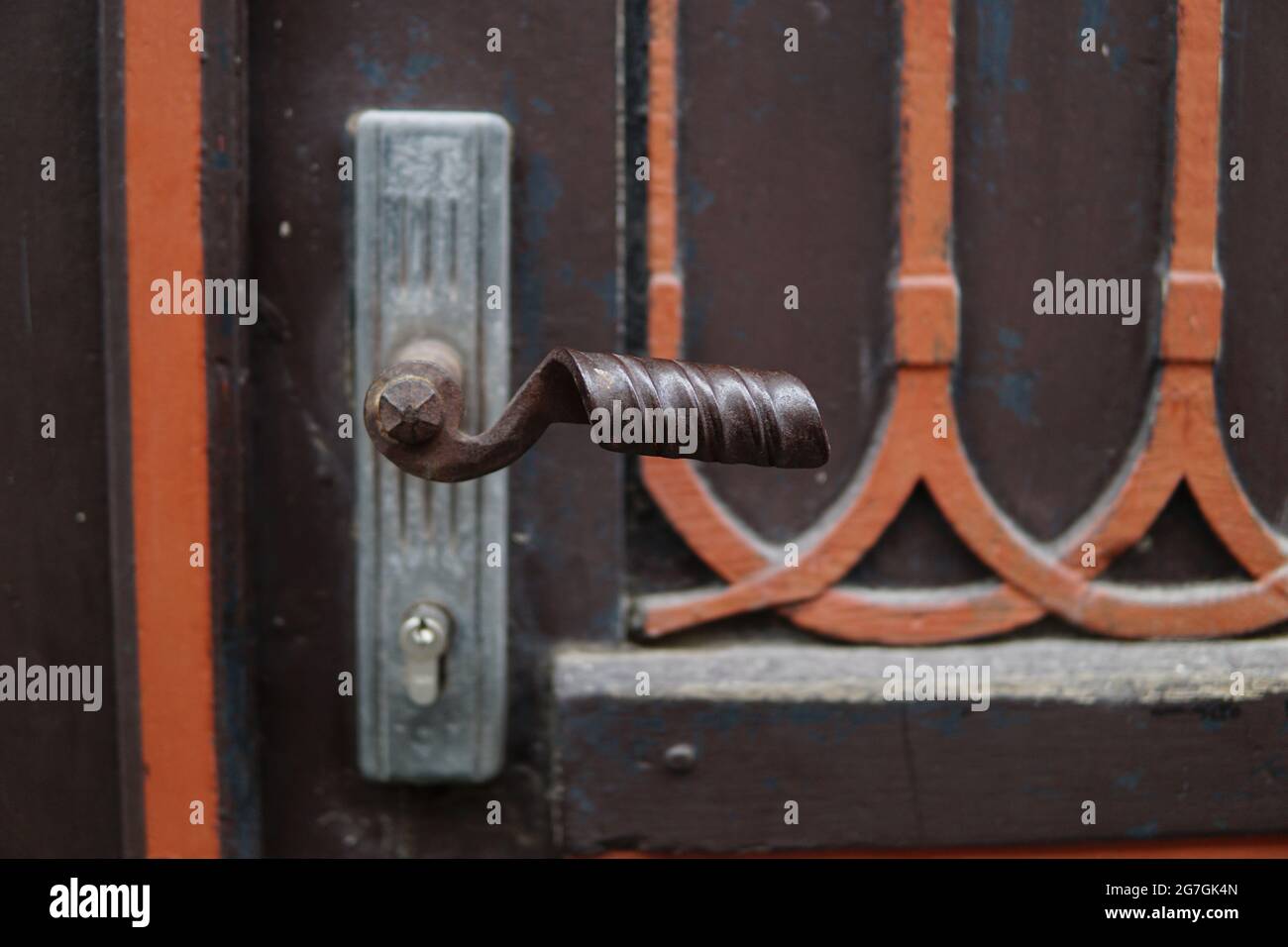 Chiusura di un pomolo vintage con maniglia in rame su una porta in legno verniciata marrone Foto Stock