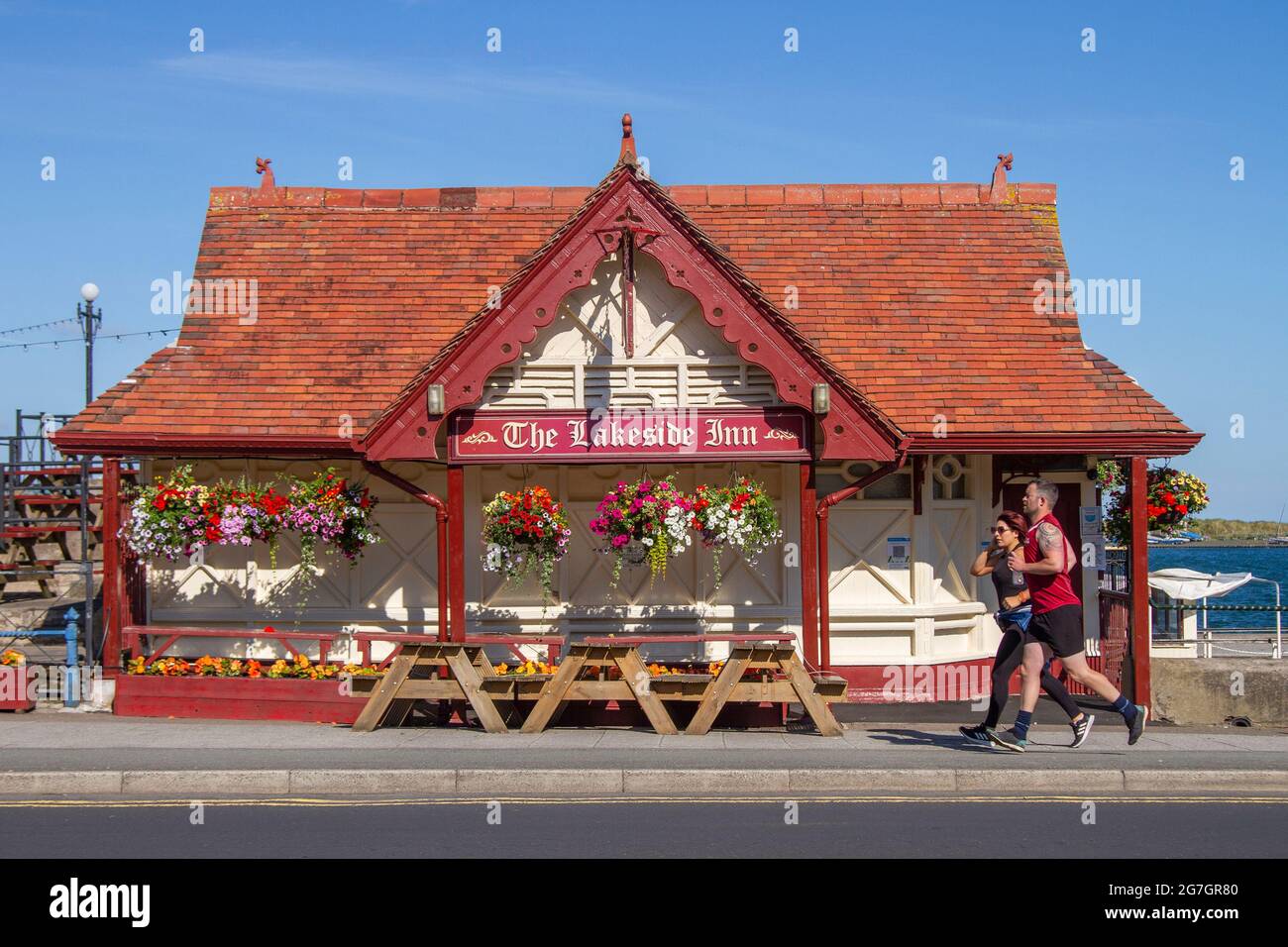 Southport, Merseyside. Regno Unito Meteo 14 Luglio 2021. Cieli estivi e venti leggeri nella località balneare, mentre la gente gode del sole della mattina presto sulla passeggiata lungomare. Lakeside Inn: Il più piccolo pub in Gran Bretagna, (presumibilmente), sul fronte mare. Credito UK; MediaWorldImages/AlamyLiveNews Foto Stock