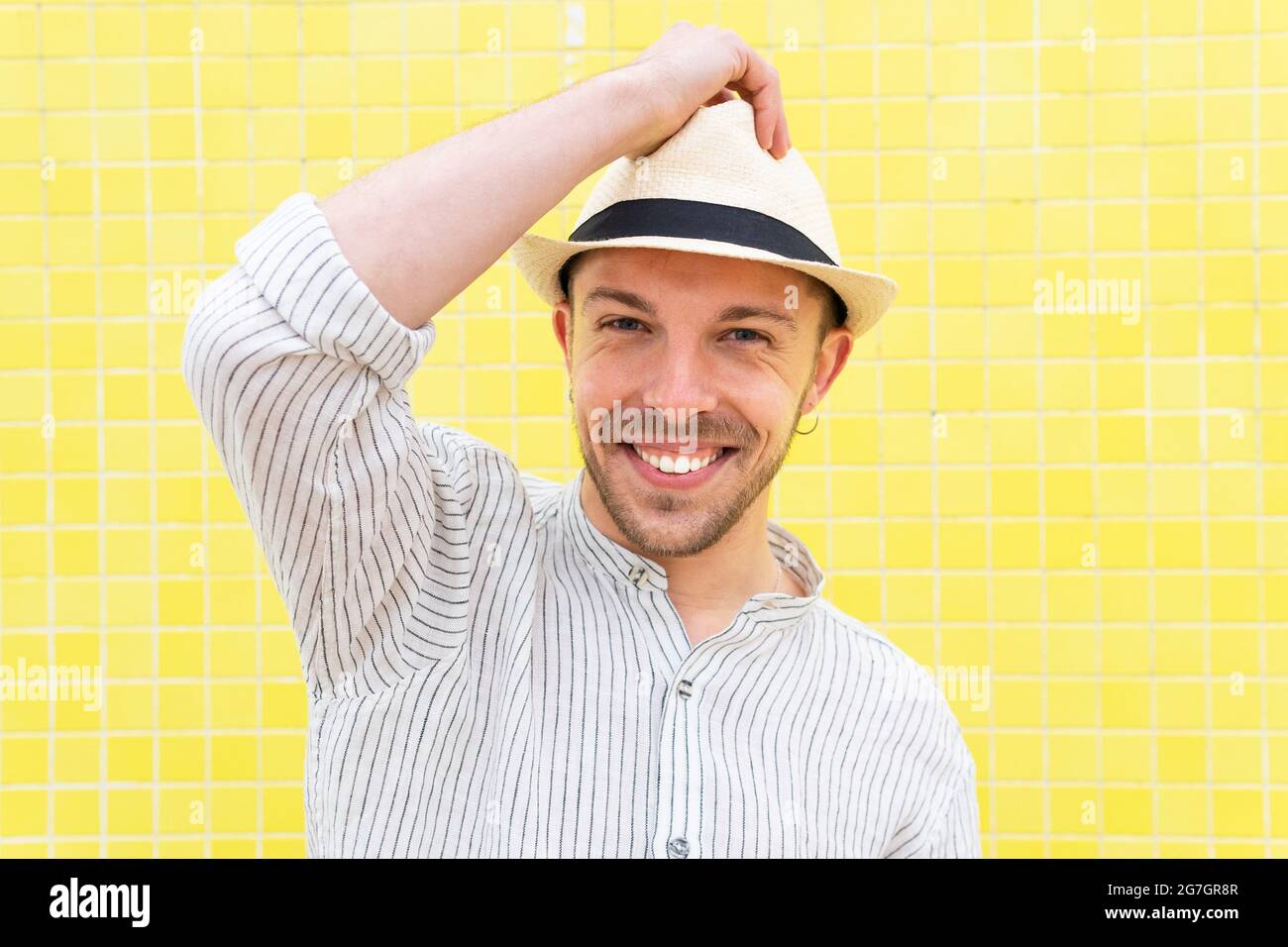 Felice ragazzo hipster sopportato giovane in outfit trendy e cappello  sorridente guardando la macchina fotografica mentre si agghiacciano da solo  contro la parete gialla nel giorno d'estate Foto stock - Alamy